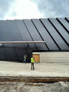 Shot of two construction workers looking up at the finished black steel cladding.