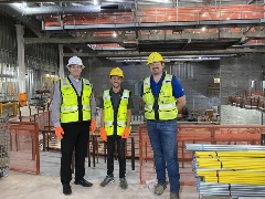Three construction workers pose and smile in the construction zone of the Steelhouse interior