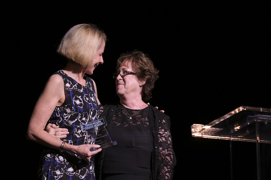 Joan Squires presents Linda Hulsey with a lifetime achievement award on stage at the Orpheum Theater
