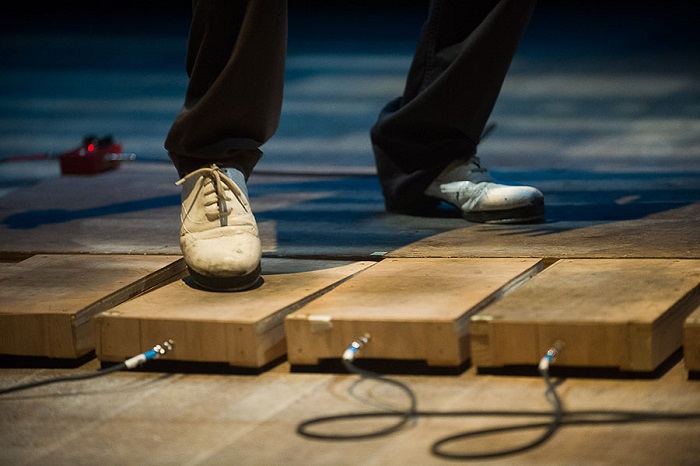 A dancer's foot wearing a tap shoe steps onto an electric block. The blocks turn the tap dance moves into music.