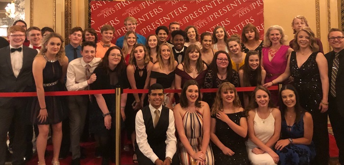 Emily and dozens of students take a group photo on the red carpet of the Showcase