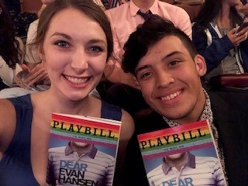 A woman and man take a selfie, smiling and holding two Playbills to "Dear Evan Hansen"