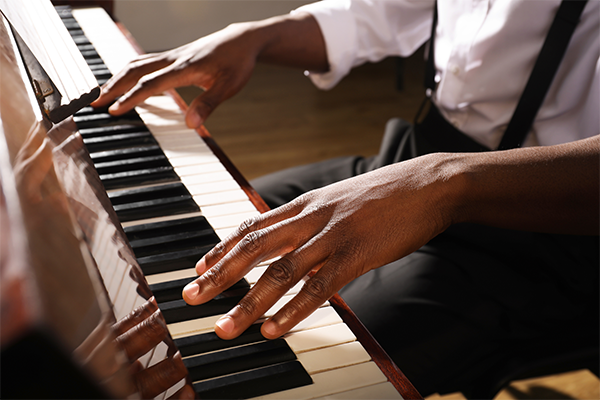 Close up of a Black person's hands playing piano.