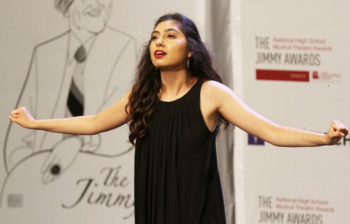 Sierra rehearses a song, arms outstretched, during practice time with a Jimmy Awards backdrop in the background.