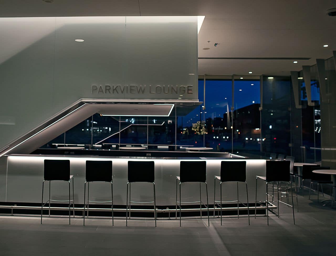 small bar area under a staircase with high top chairs