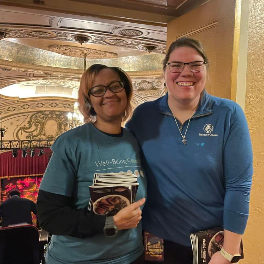 two women stand in front of a theater hall with program books