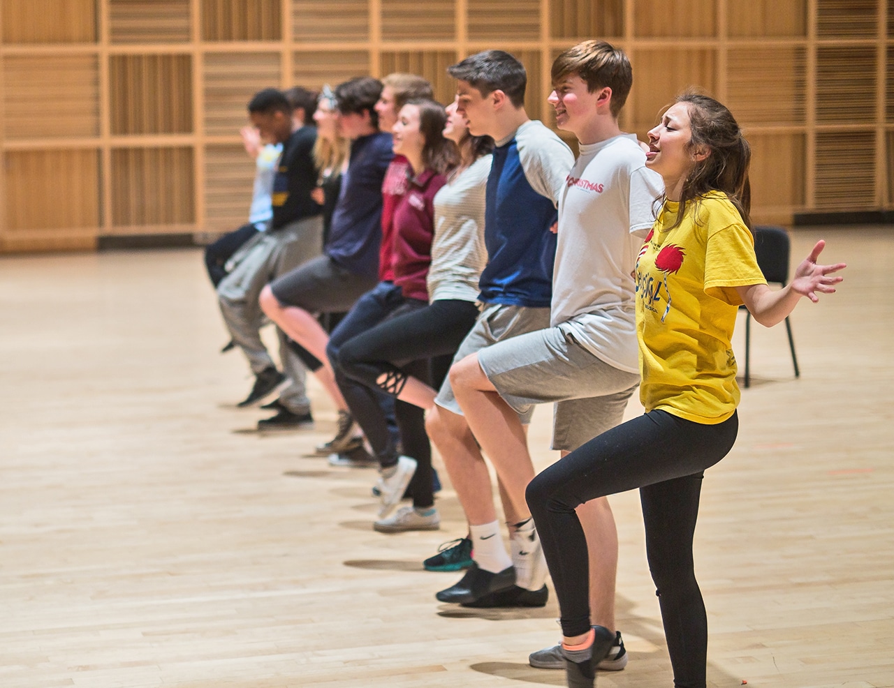 Group of young people standing in a line in a studio practicing choreography and sining