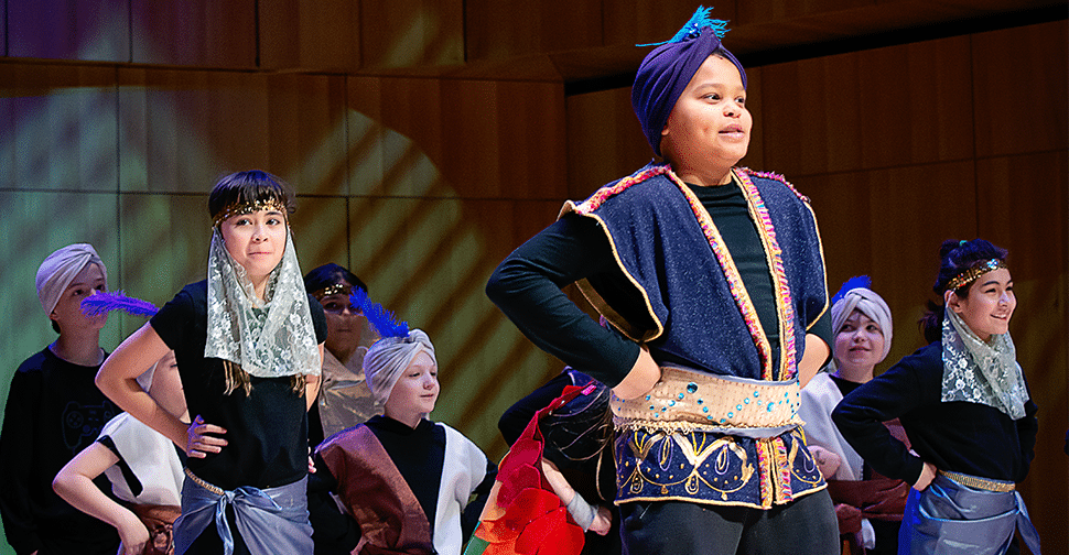 Students perform on stage in Aladdin costumes